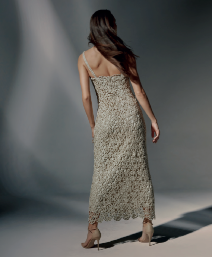 Modelo de frente luciendo el Vestido Andrea largo de crochet color beige, con tirantes finos y tejido de flores, en un estudio de estilo minimalista.