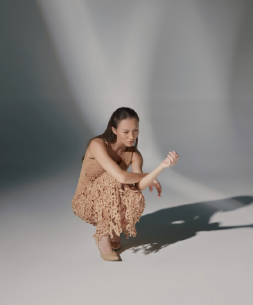 Modelo de frente luciendo el Vestido Ximena largo de crochet tipo red en negro y dorado, con escote en V y flecos en el bajo, en un estudio de fondo neutro.